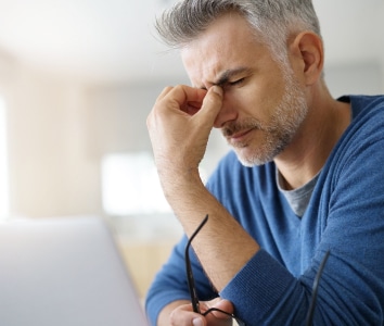 man pinching nose in pain