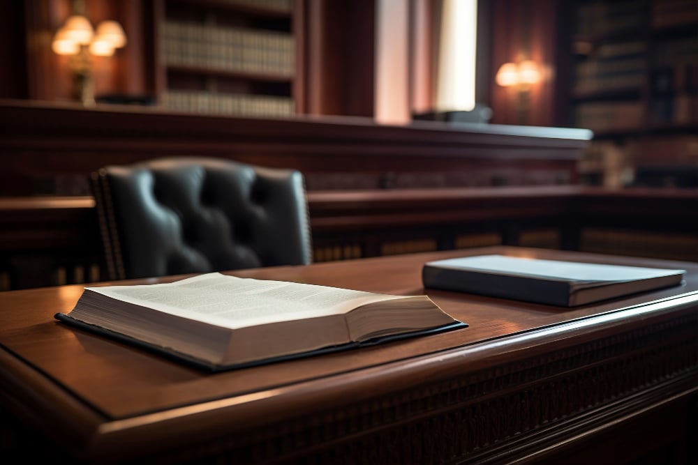 Image of a courtroom table with a chair table and two book of which one is open